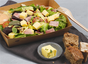 Salat med ost og skinke med brød på siden. Foto